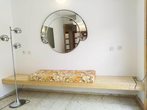 a mirror on a wall next to a wooden shelf at La Casita a 60 pasos del mar in Tamaduste