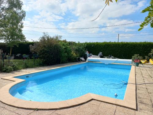 une piscine avec de l'eau bleue dans une cour dans l'établissement La ferme du bonheur, à Nouzilly