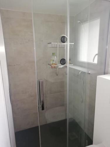 une douche avec une porte vitrée dans une salle de bain dans l'établissement Entre Terre et Mer, à Cairon