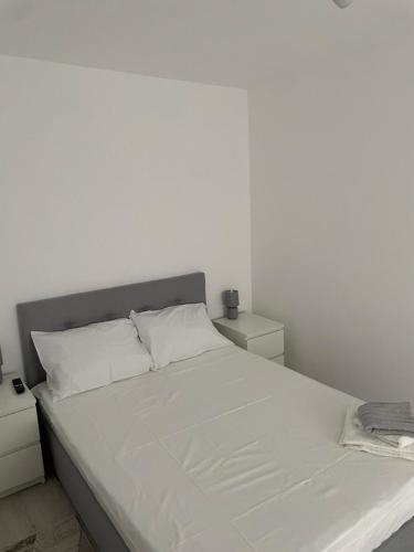 a white bedroom with a large bed with white sheets at Apartament Wave in Constanţa
