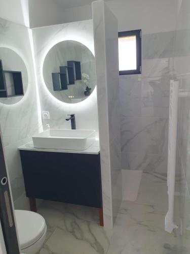 une salle de bain blanche avec un lavabo et un miroir dans l'établissement Casa Albitru, piscine, vue mer et montagne, à Figari