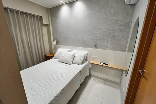 Kleines Zimmer mit einem Bett mit weißer Bettwäsche und Kissen in der Unterkunft Makia Beach Experience in Ipojuca