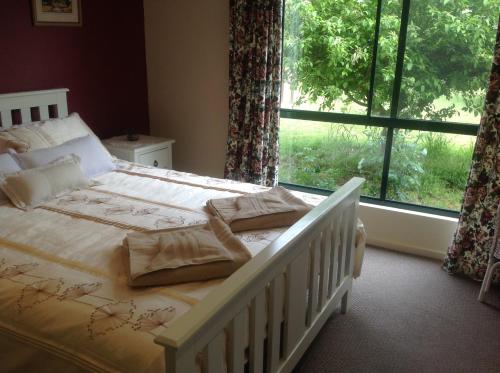 a bedroom with a white bed and a large window at Breakaway Farmstay in Encounter Bay