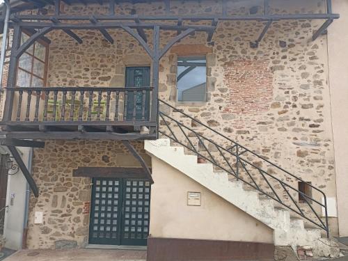 a stone building with a staircase next to a door at Le Coustalou in Livinhac-le-Haut