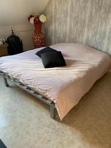 - un lit avec un oreiller noir dans la chambre dans l'établissement Chambres à louer, à Ruaudin