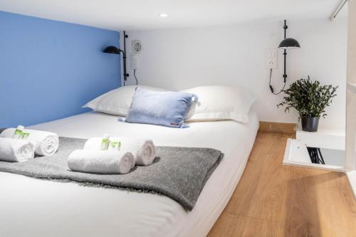 une chambre avec un lit blanc avec des serviettes dessus dans l'établissement Lavie Maison Petite Studio, à Paris