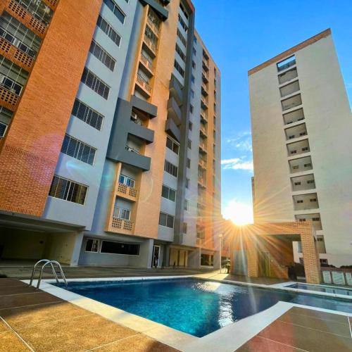 a hotel with a swimming pool in front of two tall buildings at Apartamento Ejecutivo Valencia Excelente Ubicación in Valencia