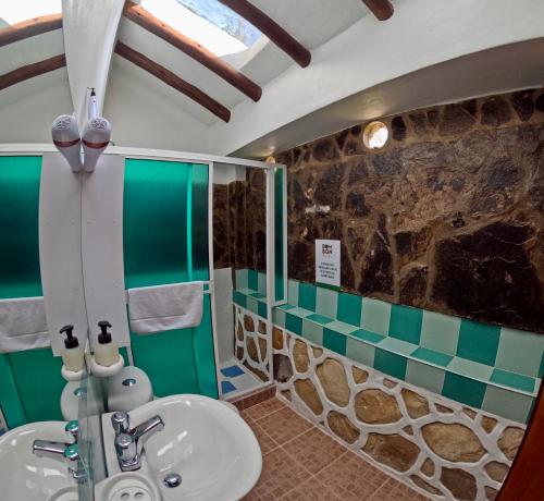 Un baño con lavabo y pared de piedra. en Bombon Hotel, en Villa de Leyva