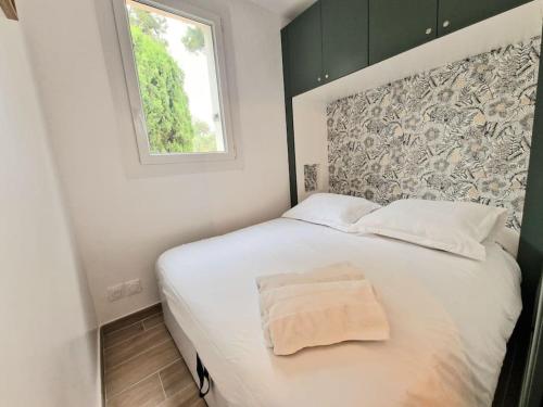 une chambre avec un lit blanc avec une fenêtre dans l'établissement T2 neuf, parking privé,accès mer, à Bandol