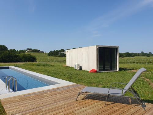 une maison avec une piscine et deux chaises sur une terrasse dans l'établissement Un loft original au milieu des vignes, à Lugasson