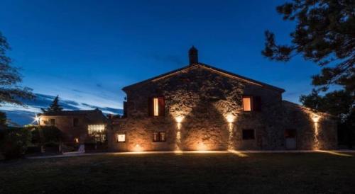 a large stone building with lights on it at night at Podere Poggiolo in Trequanda