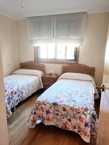 a bedroom with two beds and a window at Edificio Fonte de Ons con piscina in Noalla