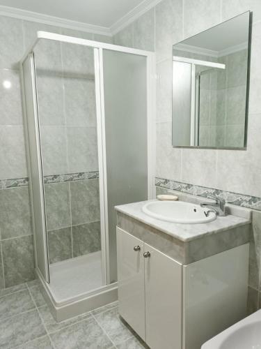 a white bathroom with a shower and a sink at Edificio Fonte de Ons con piscina in Noalla
