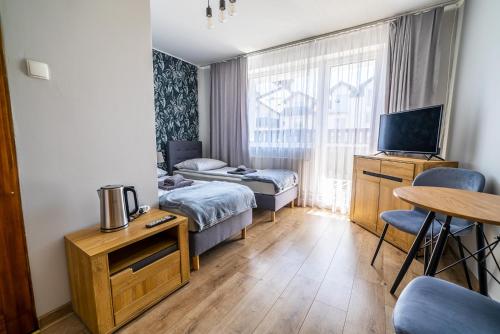 a small hotel room with two beds and a table at Niebieska Willa in Jastarnia