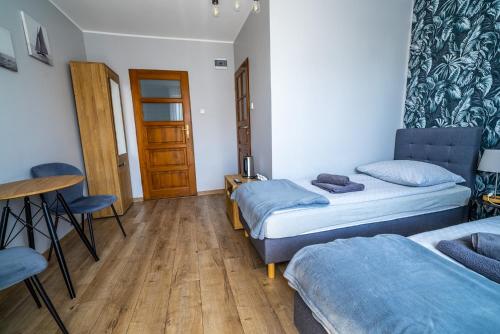 a room with two beds and a table and a door at Niebieska Willa in Jastarnia