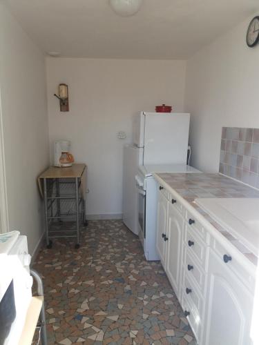 a kitchen with a white refrigerator and a table at Village in Sainte-Marguerite-de-Carrouges