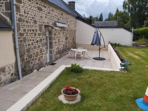 a patio with a table and an umbrella in a yard at Village in Sainte-Marguerite-de-Carrouges