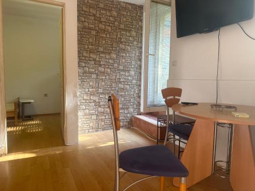 a living room with a table and a brick wall at Apartment GreenTerrace next to TC BIG FASHION Mall in Karaburma
