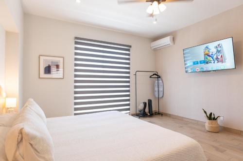 a bedroom with a white bed and a flat screen tv at New Casa Balandra with Gated Parking at Casas Sanblu in Ensenada