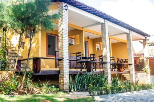 a yellow house with tables and chairs on the porch at Pousada Saruê Praia de Ponta Negra Natal RN in Natal