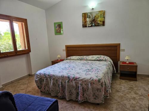 a bedroom with a bed and two tables and a window at Case Vacanze Macchione in Capo Vaticano
