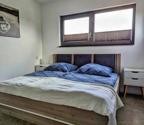 a bedroom with a bed with blue sheets and two windows at Bergkultur Sauerland in Medebach