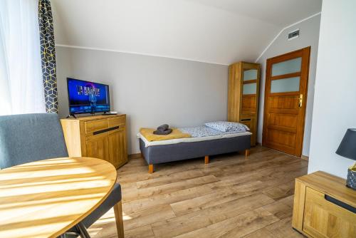 a room with a bed and a table and a tv at Niebieska Willa in Jastarnia