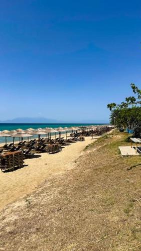 a beach with chairs and umbrellas and the ocean at Aikaterini's House in Vergia