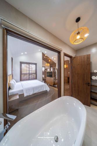a bathroom with a bath tub and a bed at Tropicana Hồ Tràm - Seashell Villa in Ho Tram