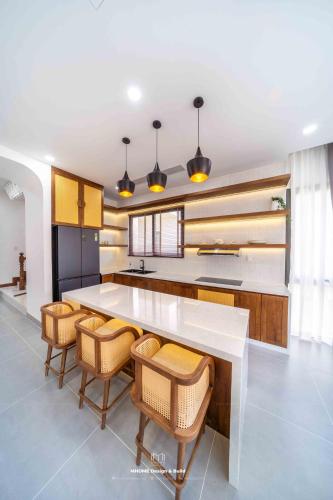 a kitchen with a large white counter and chairs at Tropicana Hồ Tràm - Seashell Villa in Ho Tram