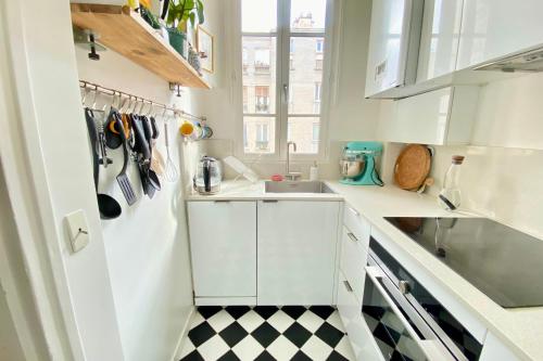 - une cuisine avec un évier et un sol en damier noir et blanc dans l'établissement Splendid apartment near La Villette, à Paris