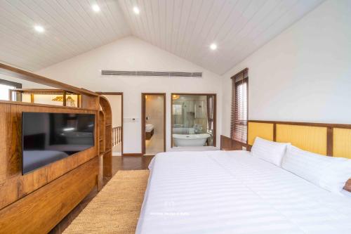 a bedroom with a large bed and a television at Tropicana Hồ Tràm - Seashell Villa in Ho Tram