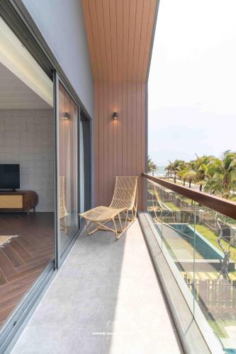 a balcony with a chair and a view of the ocean at Tropicana Hồ Tràm - Seashell Villa in Ho Tram