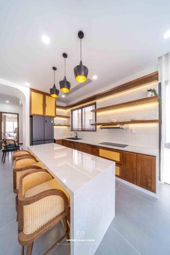 a kitchen with a large white counter and wooden cabinets at Tropicana Hồ Tràm - Seashell Villa in Ho Tram