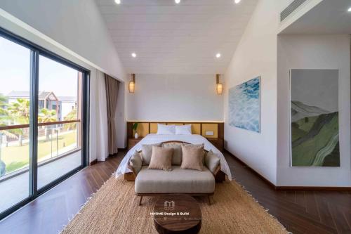 a bedroom with a bed and a couch and a large window at Tropicana Hồ Tràm - Seashell Villa in Ho Tram