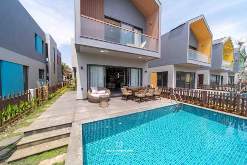 a house with a swimming pool next to a house at Tropicana Hồ Tràm - Seashell Villa in Ho Tram
