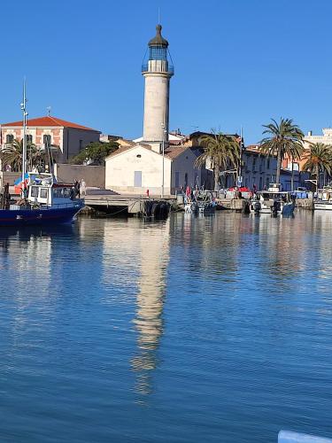 un phare dans un port avec des bateaux dans l'eau dans l'établissement T1 dans immeuble sur plage, au Grau-du-Roi