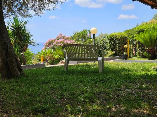 a park bench sitting in the grass near a tree at Case Vacanze Macchione in Capo Vaticano