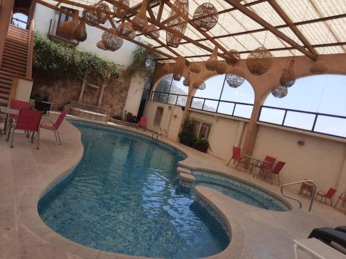 a swimming pool in a building with red chairs at Centenario Los Arroyitos in Bernal
