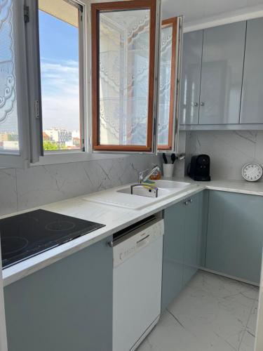 Una cocina blanca con fregadero y ventana. en Le Studio Calme et Moderne, en Saint-Maur-des-Fossés