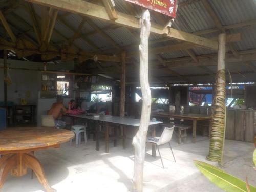 Camping Hiva Plage في Parea: مطعم فيه طاولات وكراسي وناس في الخلف