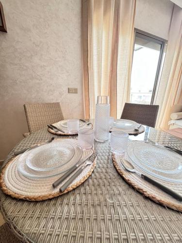 a table with plates and silverware on top of it at Saidia, résidence la perla in Saidia 