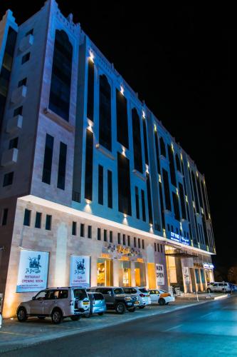 a large building with cars parked in front of it at City Park Hotel Apartments in Muscat