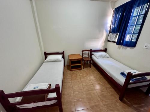 a room with two beds and a table and chairs at Hostel e Pousada Barra da Tijuca in Rio de Janeiro