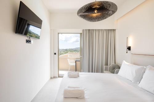 a white bedroom with a large bed and a tv at Levanda apart in Dassia