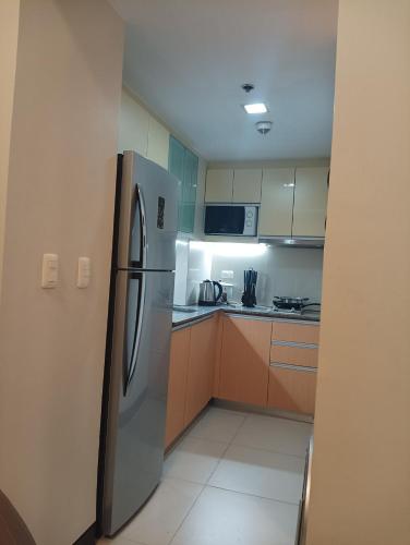 a kitchen with a stainless steel refrigerator and cabinets at Mactan Newtown Beach Condo in Mactan