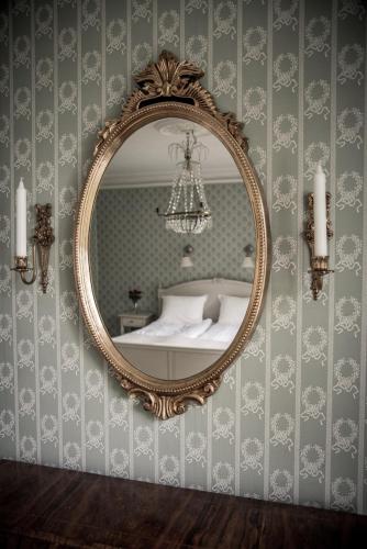 a mirror hanging on a wall with a bed at Ruders Egendom in Tibro