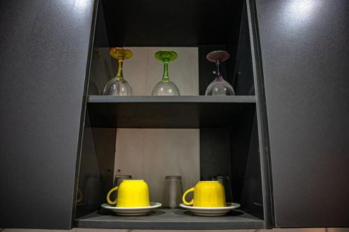 a cabinet with three yellow cups and plates on it at Opulence apartment in Karsana