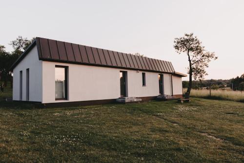 a white house with a black roof in a field at Śliwkowy Sad-Plum Orchard-Jura in Mirów
