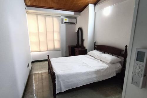 a bedroom with a bed with white sheets and a window at apartment in neiva goliat 102 in Neiva